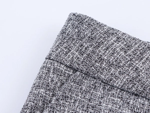 Close-up of grey tweed fabric texture showing detailed weave of the two-piece suit
