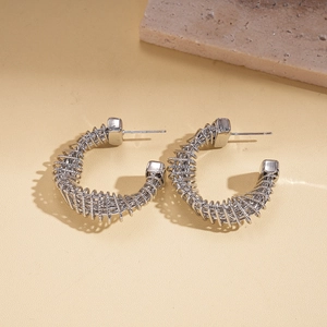 Macro detail of silver C-shape twisted metal earrings with a spiral spring texture