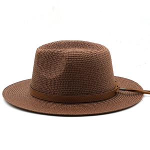 Detail of woven straw sun hat featuring brown leather band with metallic buckle and tassels