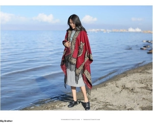 Detail of dark red paisley shawl with fringe trim worn on beach for ethnic fashion style