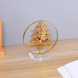 Modern gold metal Christmas tree ornament with crystal base on a wooden tabletop