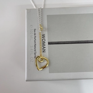 Close-up of minimalist heart pendant with mixed gold and silver tones on a gift box