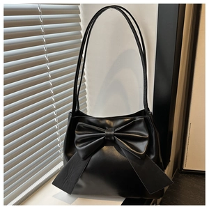 Close-up of black leather tote bag with large bow detail and sleek zipper closure