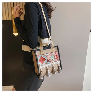 Detailed embroidery and grey tassels on ethnic linen tote bag shown on a model