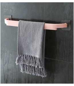 Detail of pink plastic towel rack mounted on dark tiles with adhesive hooks for bathroom