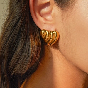 Elegante goldene Herzohrringe mit Wellenstruktur in Vintage-Optik am Ohr getragen