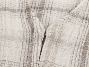 Detailansicht der beigen Karostofftextur und des Hakenverschlusses aus Metall am Kleid