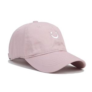 Detailed close-up of pink cotton baseball cap with white embroidered smiley face