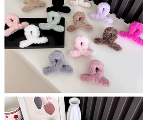 Multiple colorful plush hair claws in black, pink, and white scattered on a neat surface