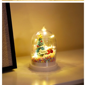 Close-up of glass dome Christmas tree lamp with warm LED lights and colorful foam balls