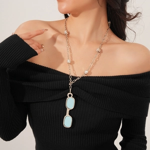 Close-up of a silver necklace with blue lens eyewear pendant and sparkling zircons