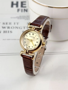 Close-up of gold quartz watch with Roman numerals and brown crocodile leather strap