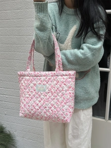 Quilted floral tote bag with pink flower patterns and woven straps in a top-down view