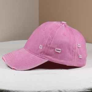Detailed close-up of pink washed cotton baseball cap with distressed torn edges
