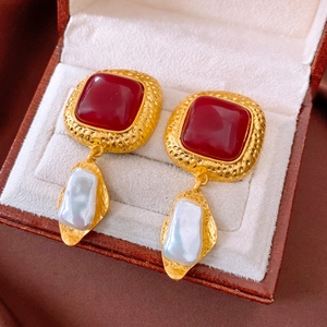 Close-up of vintage square red resin earrings with baroque pearls in a brown leather box