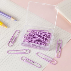 Detail of purple paper clips in a clear plastic case on a pink desk setting