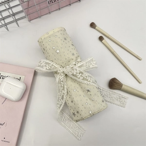 Chic beige fabric cosmetic roll-up organizer with lace ties and gold star patterns