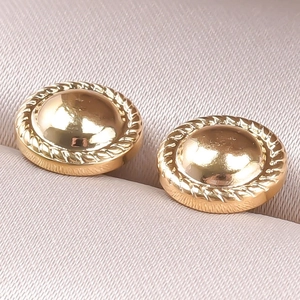 Detailed close-up of golden dome stud earrings with classic twisted rope edge on fabric