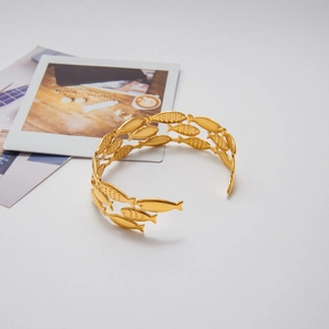 Macro shot of gold hammered fish pattern cuff bracelet on a minimalist background