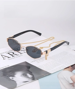 Detail of irregular polygon sunglasses with gold chain on fashion magazine