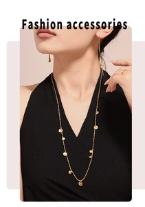 Dettaglio di collana dorata con pendenti tondi, orecchini a goccia e anello con diamante