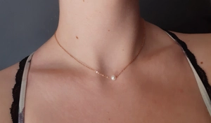 Close-up of minimalist gold pearl necklace worn on model to show the length and fit