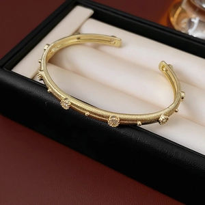 Detail of gold-plated textured open bangle with small zircons in a black jewelry box