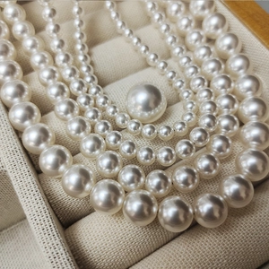 Multiple sizes of cream white pearl necklaces with high glossy finish on jewelry box