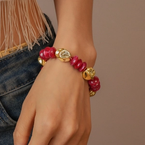 Detail of red acrylic beads and irregular gold metal pieces on a vintage beaded bracelet