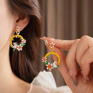 Détail de boucles d'oreilles vintage avec lapin blanc et fleurs sur anneau jaune