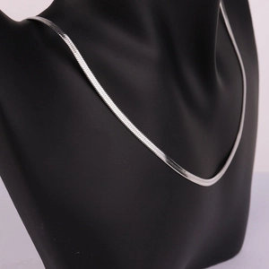 Detailed view of a silver stainless steel snake chain necklace on a black mannequin bust