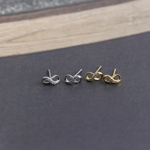 Macro detail of silver and gold infinity stud earrings with sparkling crystals