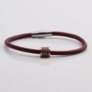 Detail of burgundy leather bracelet with rose gold zircon bead and magnetic clasp