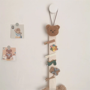 Detail view of a beige hair clip organizer belt featuring a plush bear and colorful clips