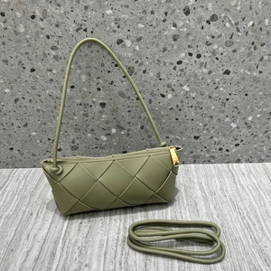 Detail of green woven leather handbag with gold hardware and matching shoulder strap