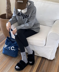 Detail of warm grey knit socks styled with black plush slippers and leisure outfit
