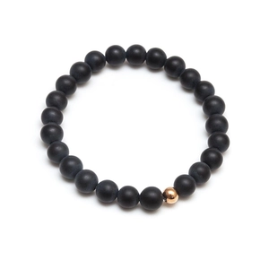 Detail of matte black lava stone beads and a single gold metal accent on the bracelet