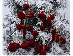Detail von roten beflockten Weihnachtskugeln mit Samtstruktur an einem Schneebaum