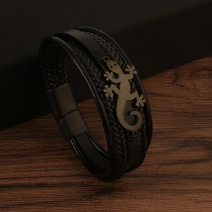 Detail of multi-layer black lizard leather woven bracelet with a metal gecko charm