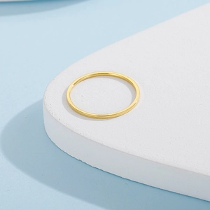 Macro view of minimalist gold thin band ring on curved white textured pedestal