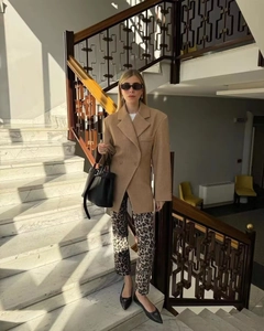 Détail d'un blazer camel assorti à un pantalon léopard sur un escalier moderne