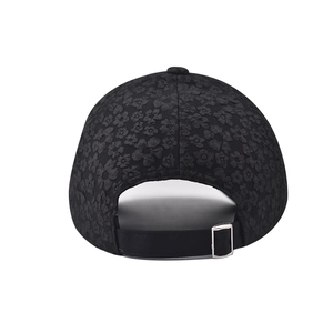 Dettaglio cappello nero in pizzo con trama floreale a rilievo e fibbia in metallo regolabile