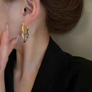Two-tone interlocking link hoop earrings in gold and silver plating worn by a model