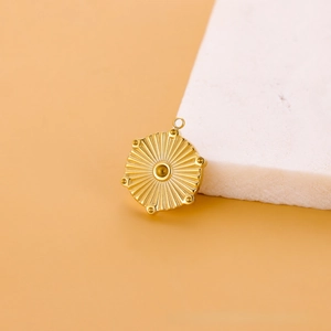 Détail macro d'un pendentif soleil doré avec texture radiale sur socle pierre