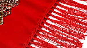 Detail of red paisley scarf featuring fine twill texture and long fringe tassels