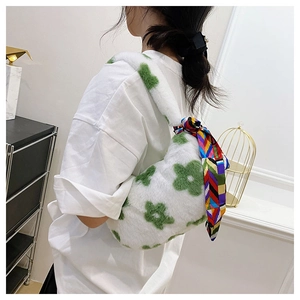 Close-up of white plush handbag featuring green floral patterns and a colorful silk scarf