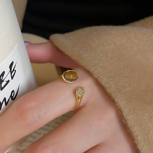 Detail of cross-over open ring with oval tiger eye stone and pavé zircon on gold band