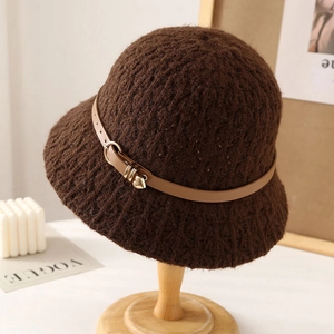 Brown knit bucket hat with leather belt and gold heart pendant on a wooden stand