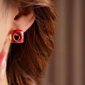 Macro detail of French vintage square red enamel hoop earring on model with golden base