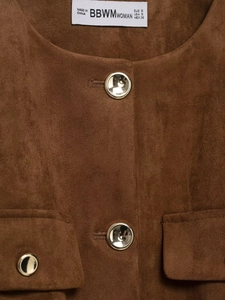 Détails du col d'un blazer en daim avec étiquette et boutons dorés métalliques